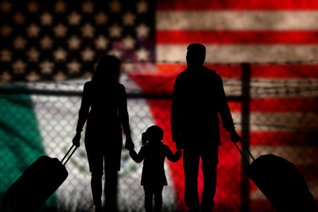 immigrant family in front of a chain link fence