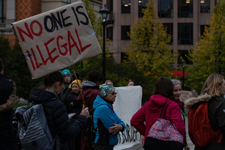 woman holding no one is illegal sign